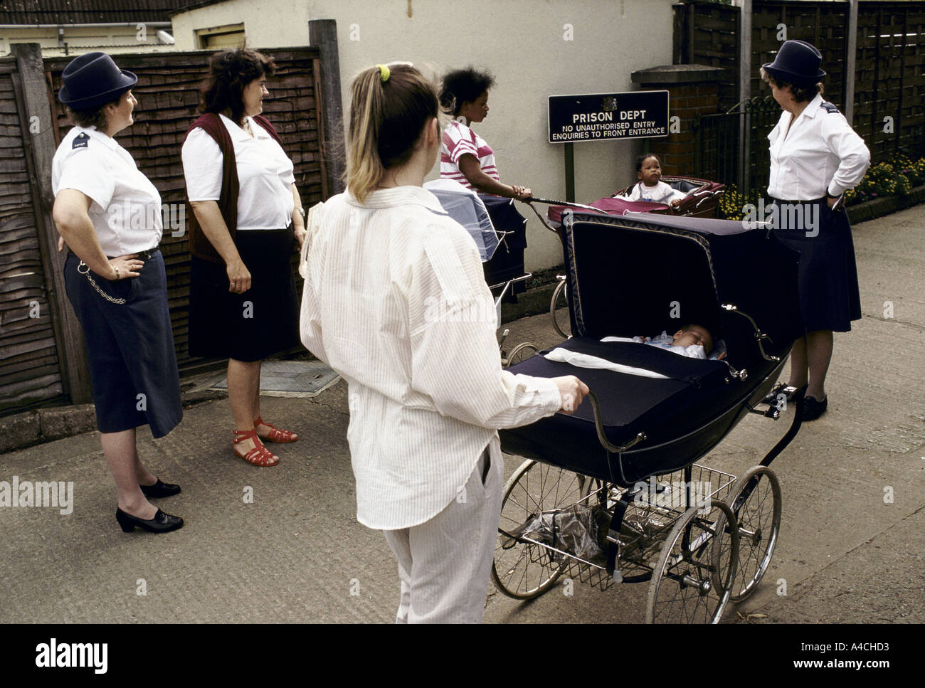 Hier zwei Gefängniswärter begleiten drei Mütter und ihre Babys in ihren Kinderwagen in einen Spaziergang über das Gelände Gefängnis. " Stockfoto