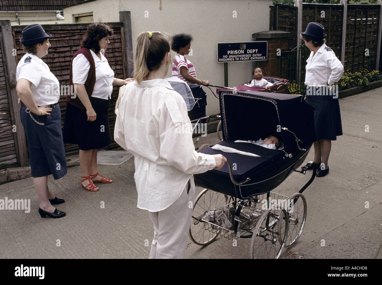 Hier zwei Gefängniswärter begleiten drei Mütter und ihre Babys in ihren Kinderwagen in einen Spaziergang über das Gelände Gefängnis. " Stockfoto