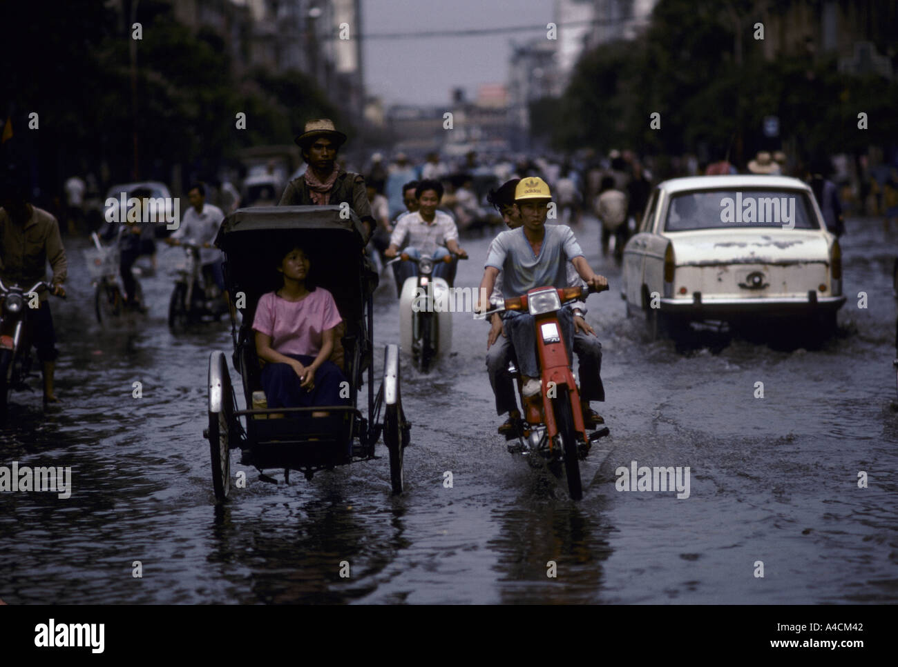 Phnom Penh; Verkehr von Rikschas, Fahrräder und Autos bewegt sich durch überflutete Straßen nach dem Monsunregen. Stockfoto