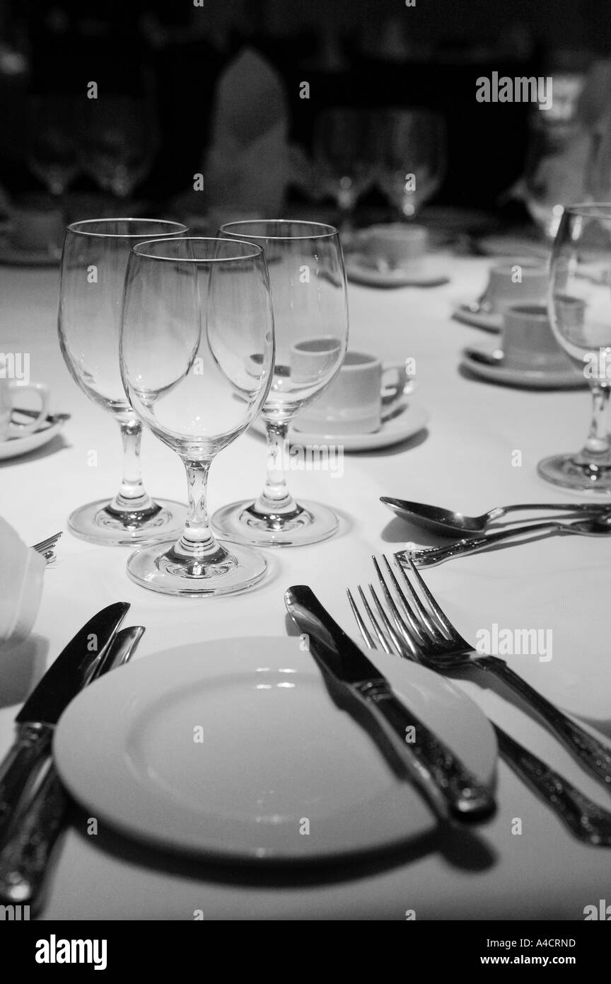 Esstisch-Einstellung auch ein Messer Gabel Löffel Teller und Gläser auf einer weißen Tischdecke mit aufrechten Servietten in schwarz Stockfoto