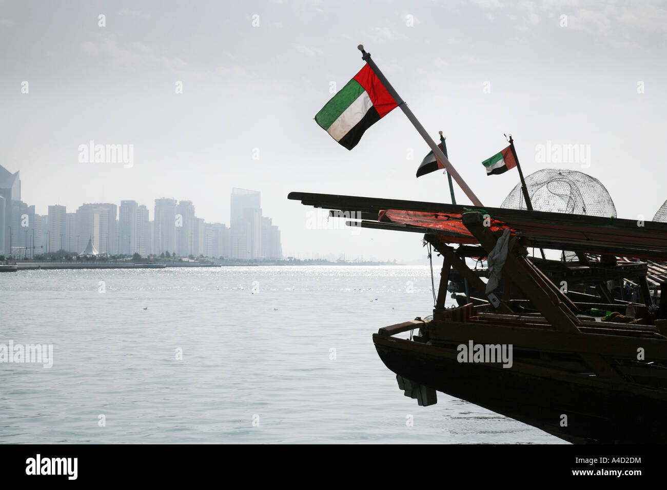 Traditionelle Dhaus und ihre Flaggen im Hafen gegen die moderne Skyline, Abu Dhabi, Vereinigte Arabische Emirate Stockfoto