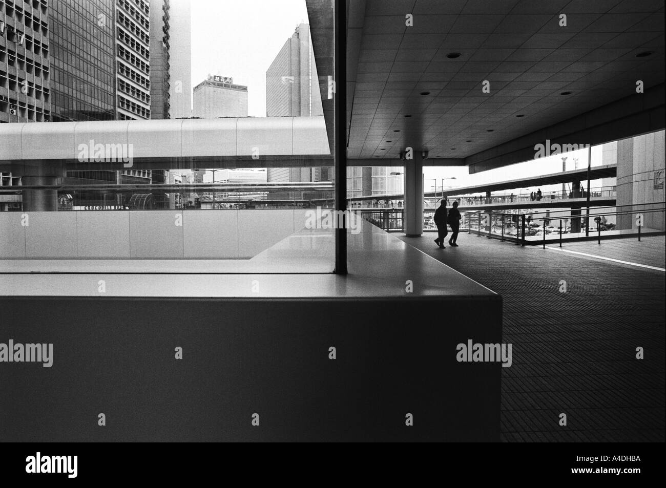 Zwei einsame Menschen, gesehen durch die obenliegende Wege zwischen Bürogebäuden, Hong Kong, China Stockfoto