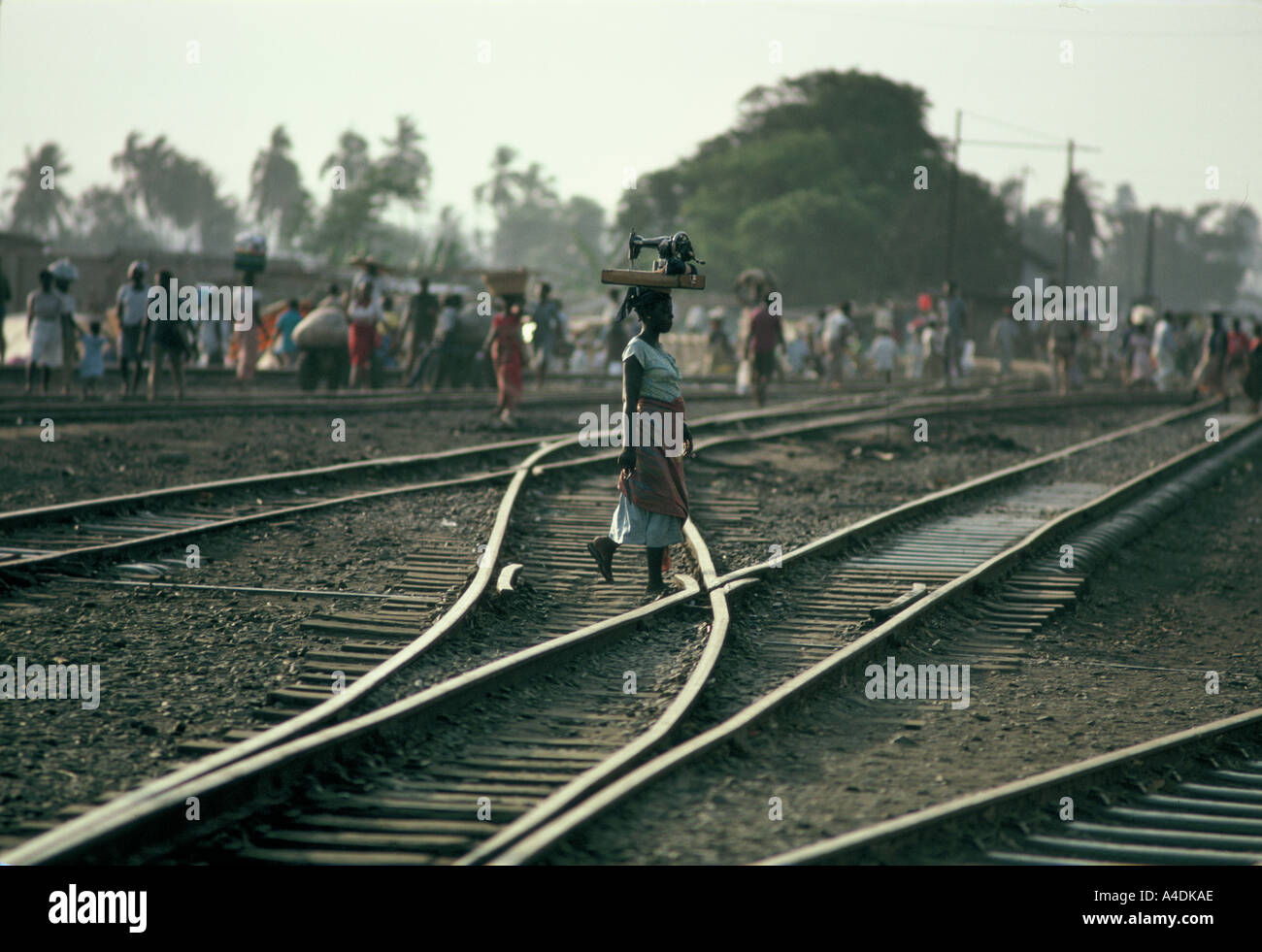 Eine Frau mit einer Nähmaschine auf dem Kopf überquert die Bahngleise, Accra, Ghana Stockfoto