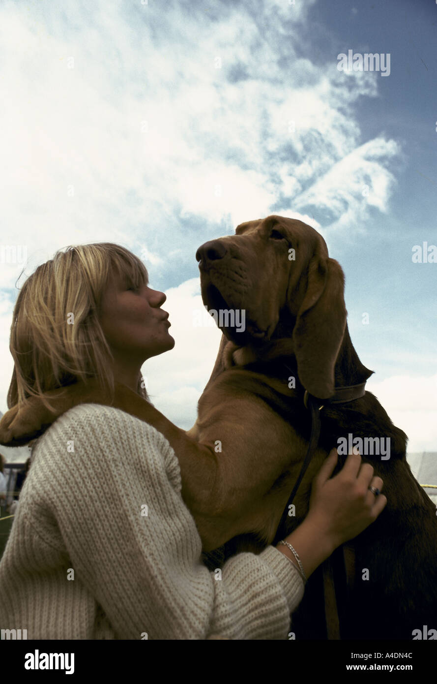Eine weibliche Besitzer küssen ihr Hund, der auf seinen Hinterbeinen mit seinen Pranken auf ihre Schultern beim Bloodhound-Wettbewerb steht Stockfoto