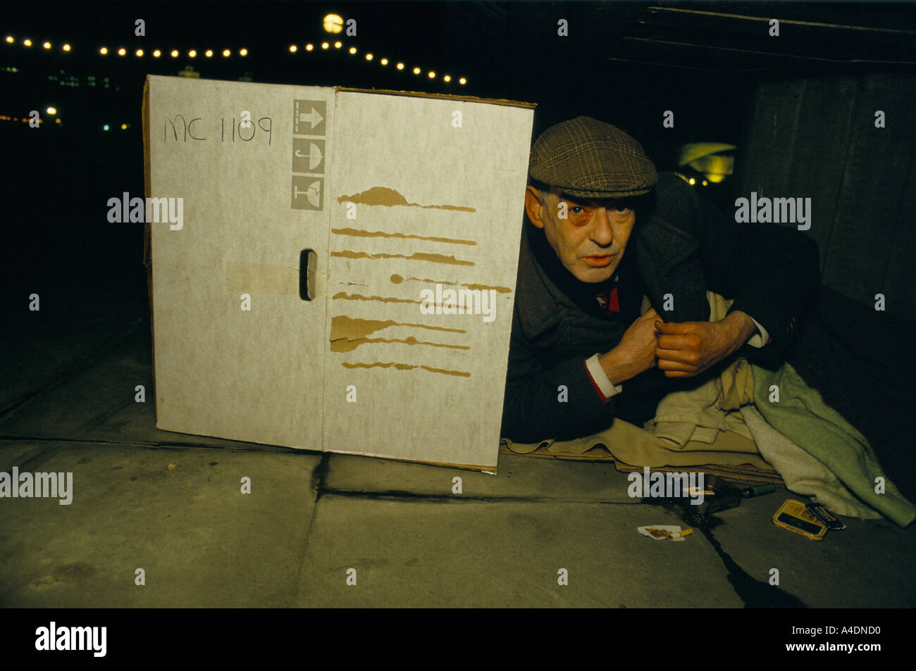Ein Obdachloser mit einem blauen Auge schlafen rau hinter Pappe, rollt eine Zigarette Royal Festival Hall, London Stockfoto