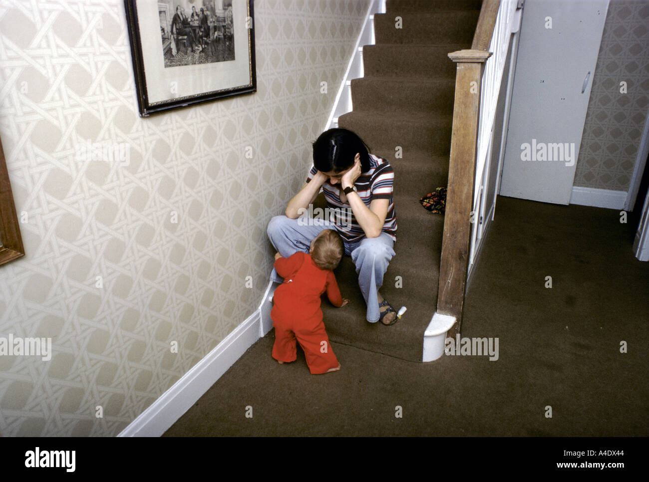 Frau sitzt auf einem Schritt am unteren Ende der Treppe mit Kind sah sie an Depressionen leiden Stockfoto