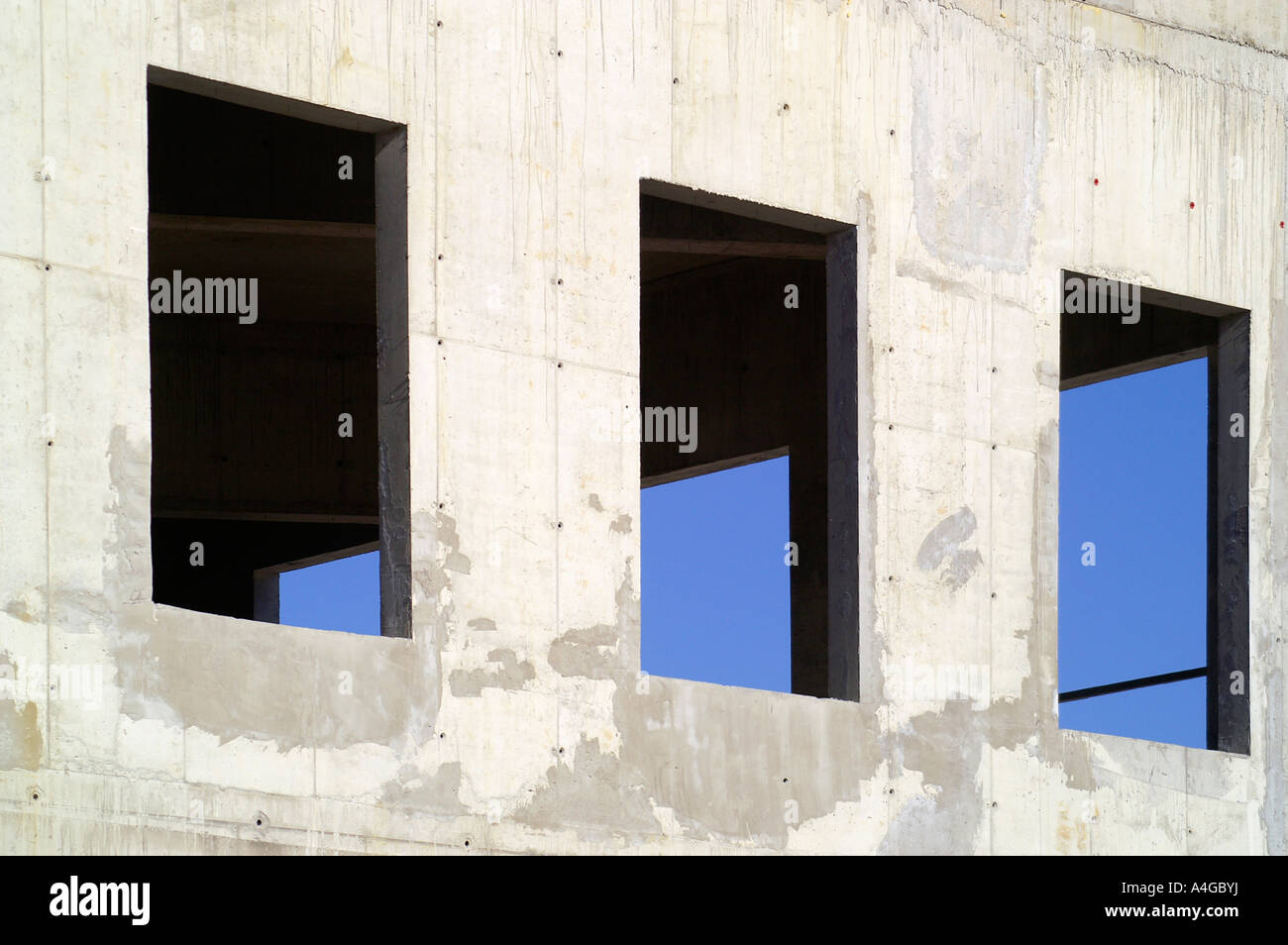 Drei rechteckige Öffnungen in der Betonwand, Loch für Windows, Baustelle, blauer Himmel Stockfoto