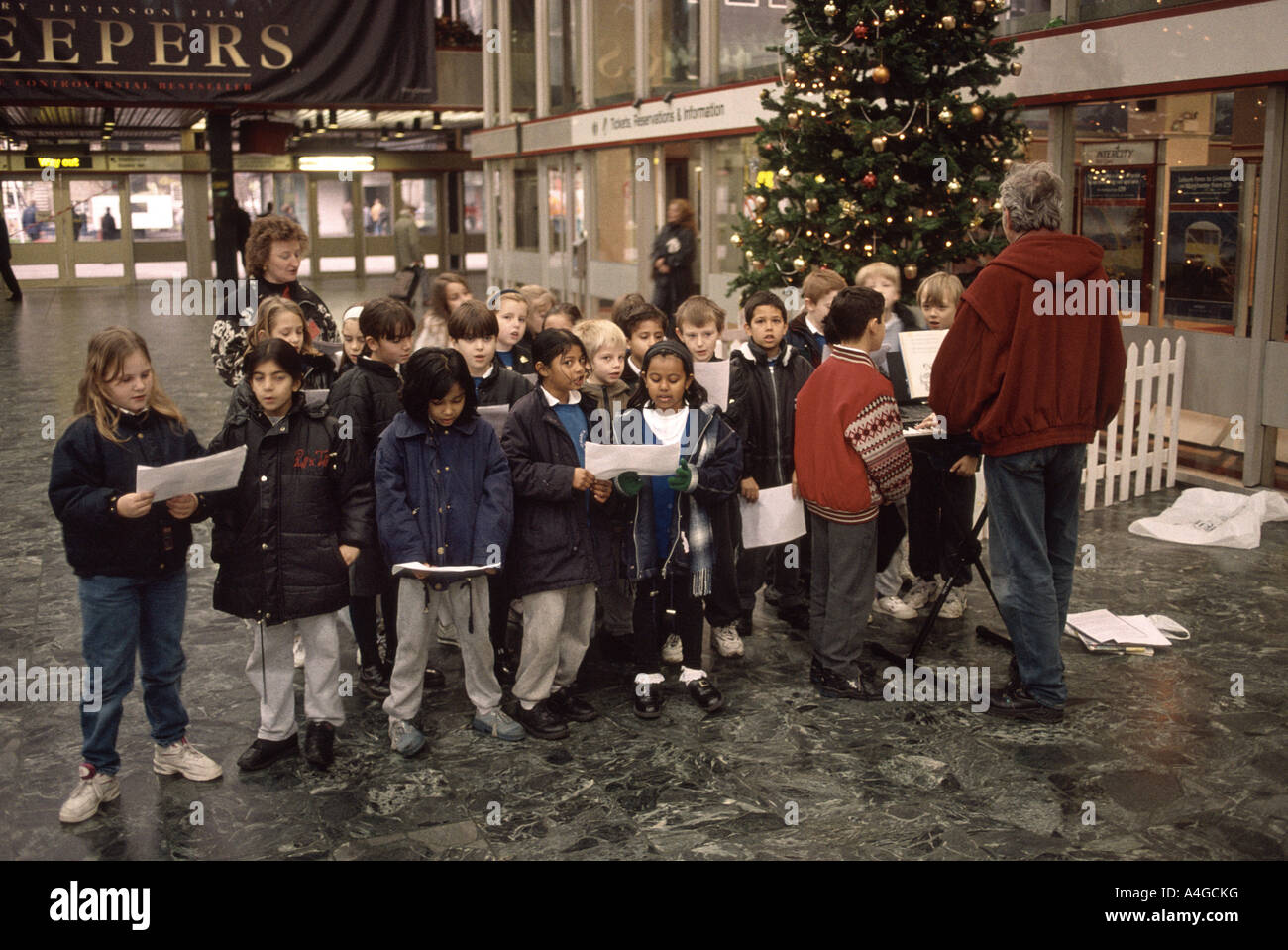 Kinder singen Weihnachtslieder in einem Bahnhof Stockfoto