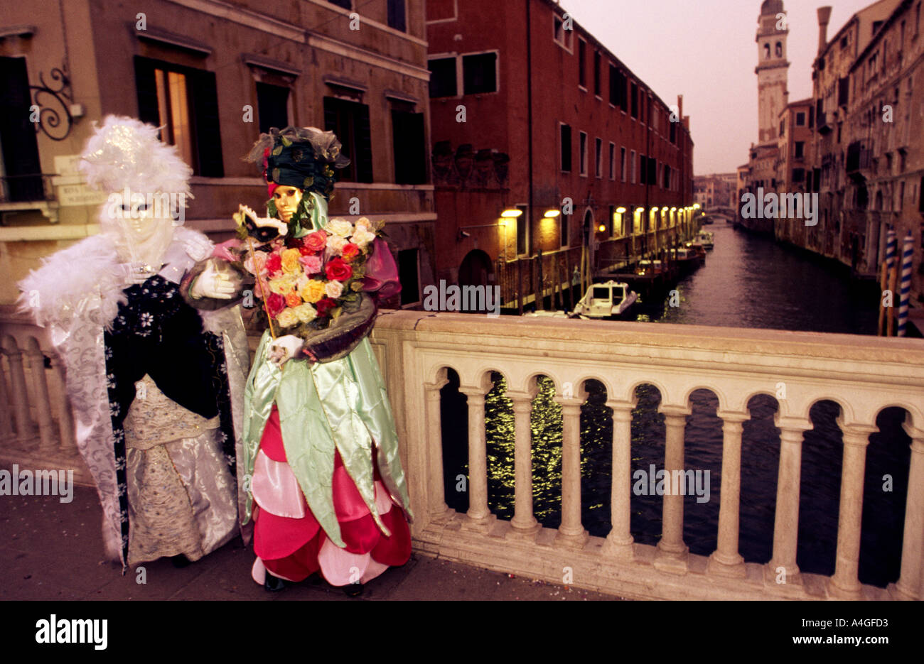 Zwei Personen auf einer kleinen Brücke über Kanal gekleidet in aufwendigen Kostümen und Masken für den jährlichen Maskerade-Karneval in Venedig Italien Stockfoto