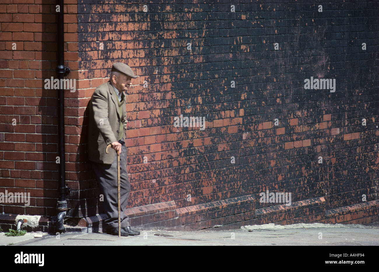 Alter Mann stützte sich auf Wand in Barry South Wales UK Stockfoto