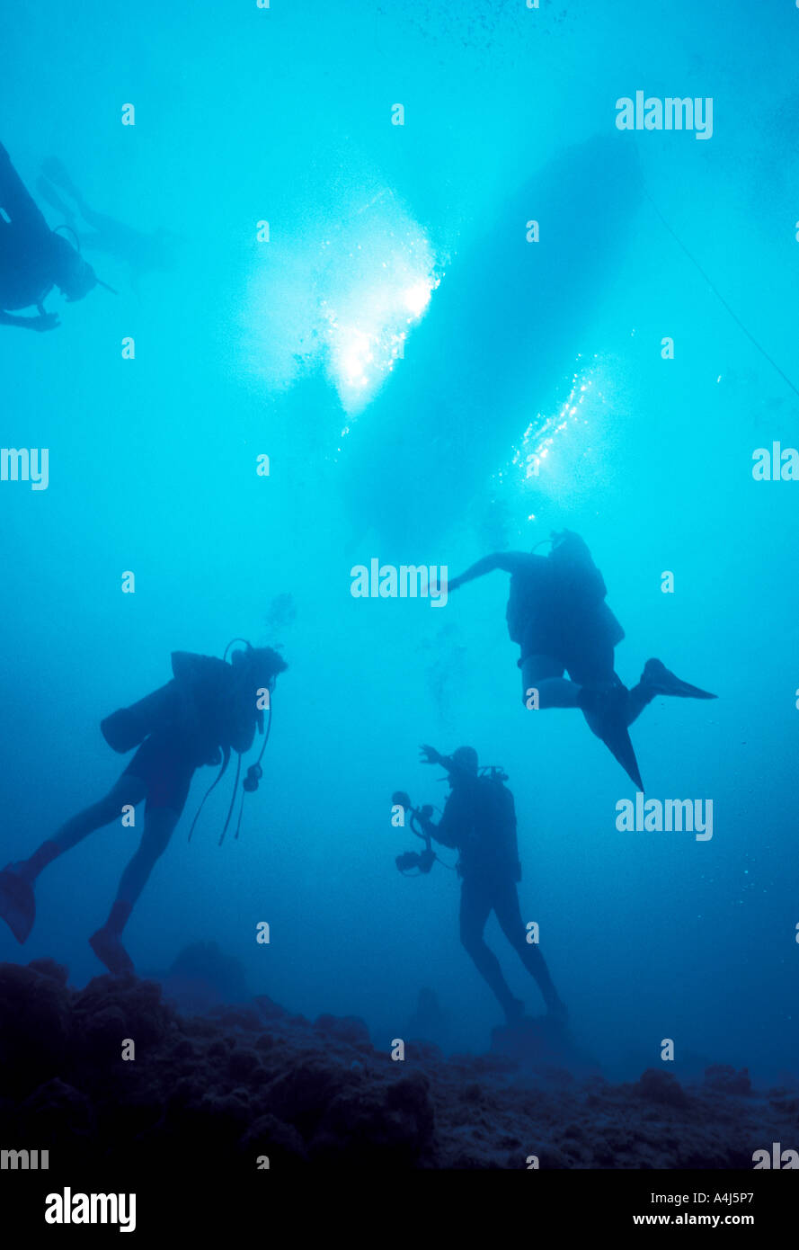 Unterwasser Taucher Silhouetten schwimmen zur Oberfläche mit Tauchboot und strahlende Sonne im Hintergrund Stockfoto