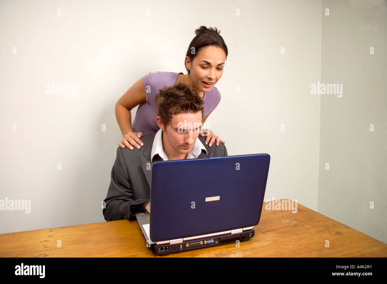 Mann mit einer Frau auf der Suche über die Schulter, die Arbeit am Laptopcomputer überrascht Stockfoto