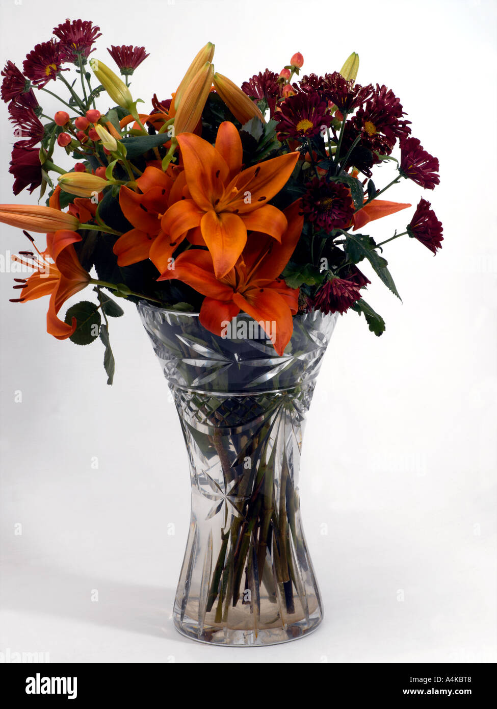 Vase mit Blumen Orange Lilien und lila Margeriten mit Glitzer in führen Kristallvase Stockfoto