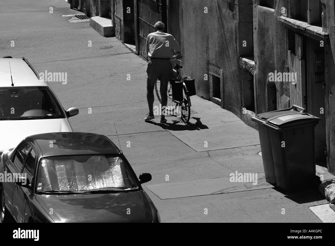 Alter Mann zu Fuß, mit Fahrrad auf Bürgersteig, Rückansicht Stockfoto