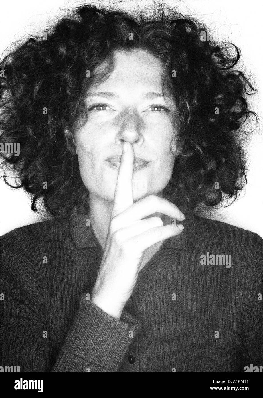 Lächelnde Frau, Finger über Mund, Porträt, b&w. Stockfoto