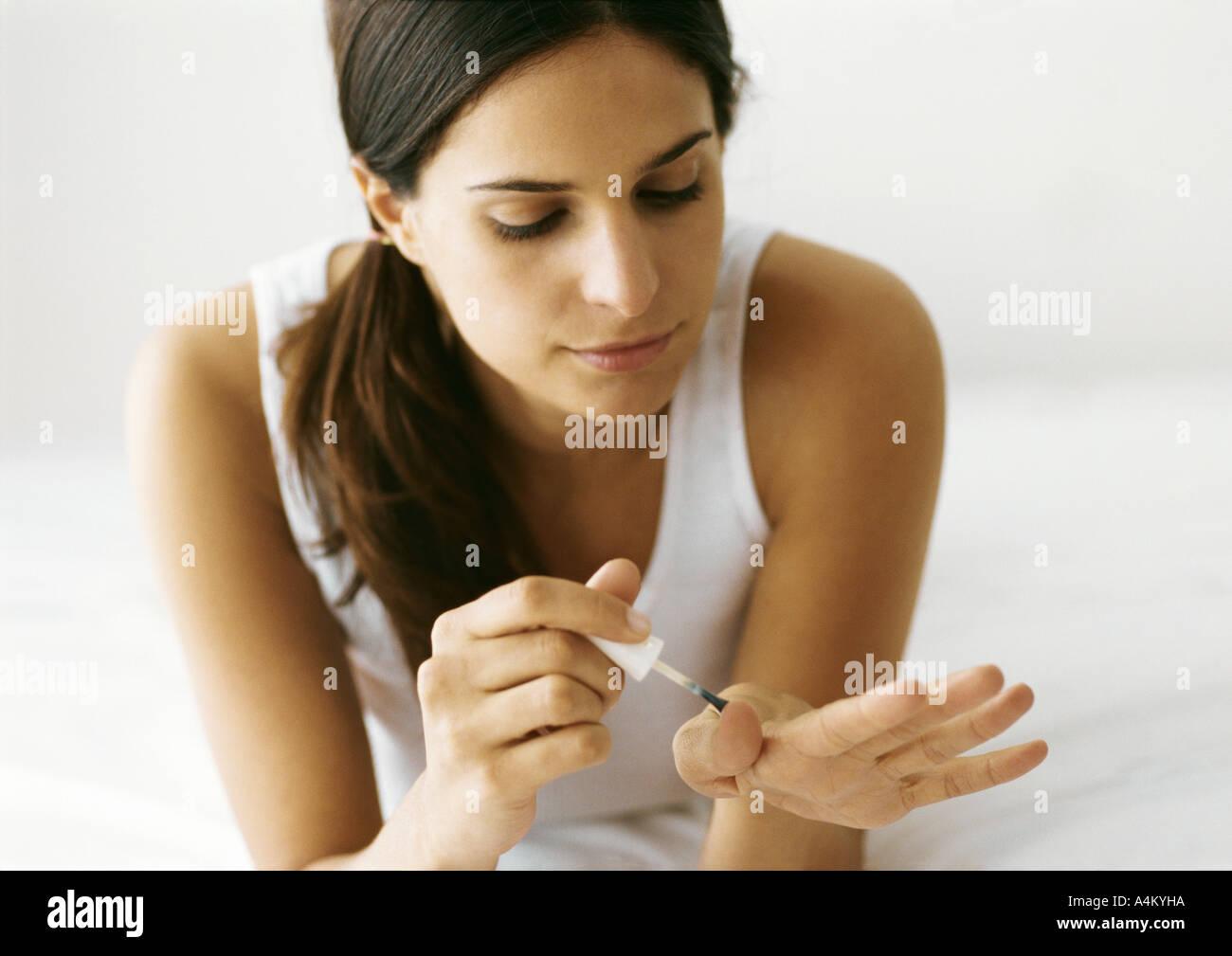Frau, Polieren der Nägel auf Bett Stockfoto