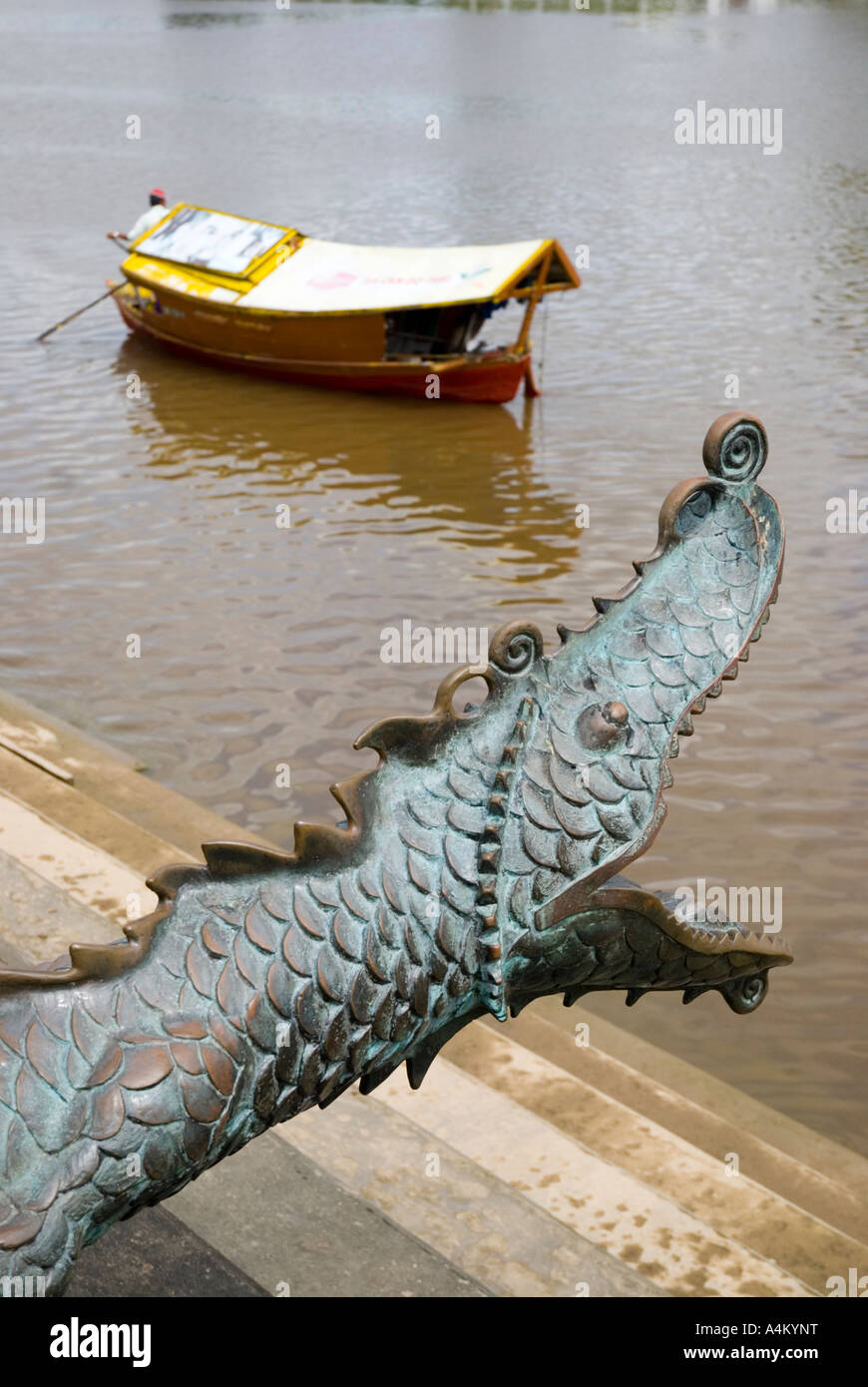 Ein Fährmann auf dem Fluss bei Kuching reiht an einer Replik chinesischer Bronzekanone in Form eines feuerspeienden Drachen vorbei Stockfoto