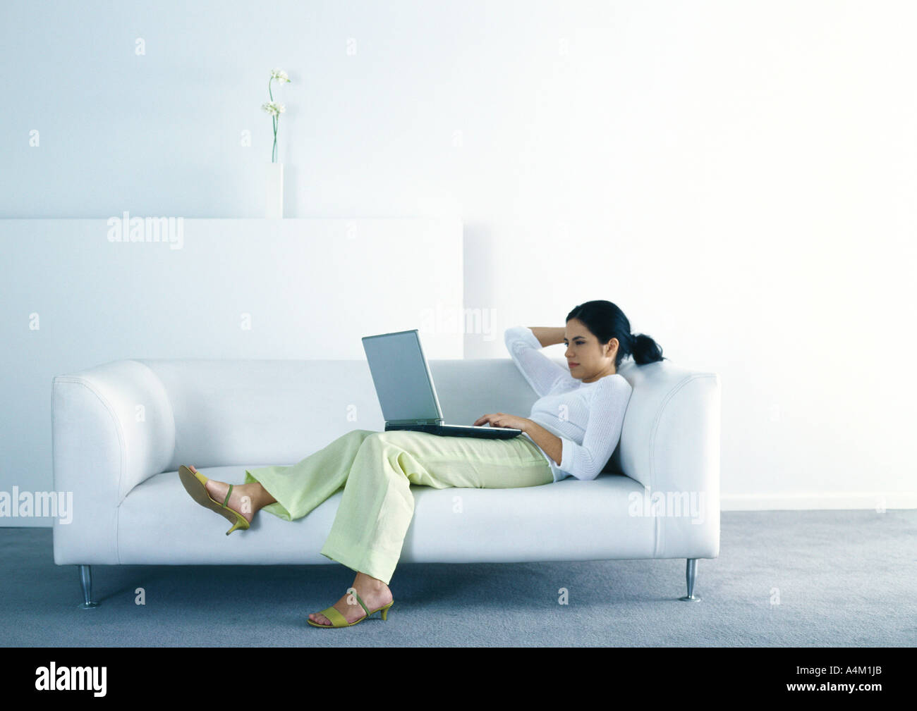 Frau auf Sofa lümmeln und Laptop verwenden Stockfotografie - Alamy