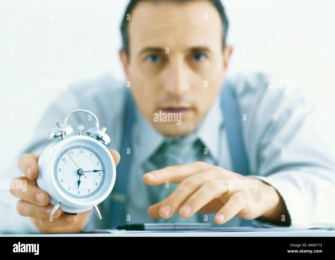 Mann hält Wecker, konzentrieren sich auf Hände und Uhr im Vordergrund Stockfoto