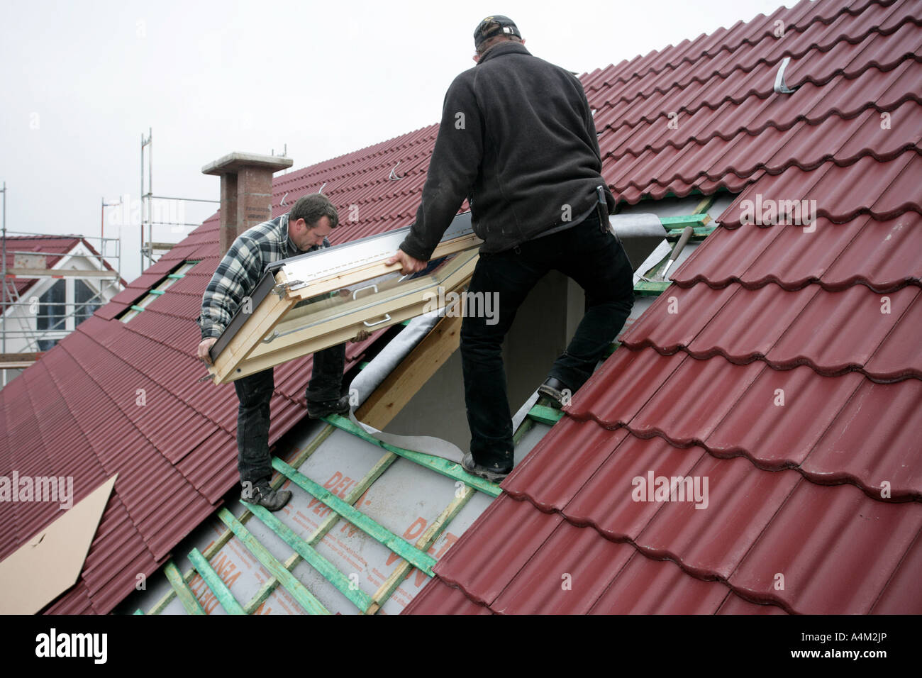 DEU-Deutschland-Essen-Fliesenleger arbeiten auf dem Dach eines Privathauses Dach Fenster Instalation Gebäudes einer Haus-Baustelle von Stockfoto
