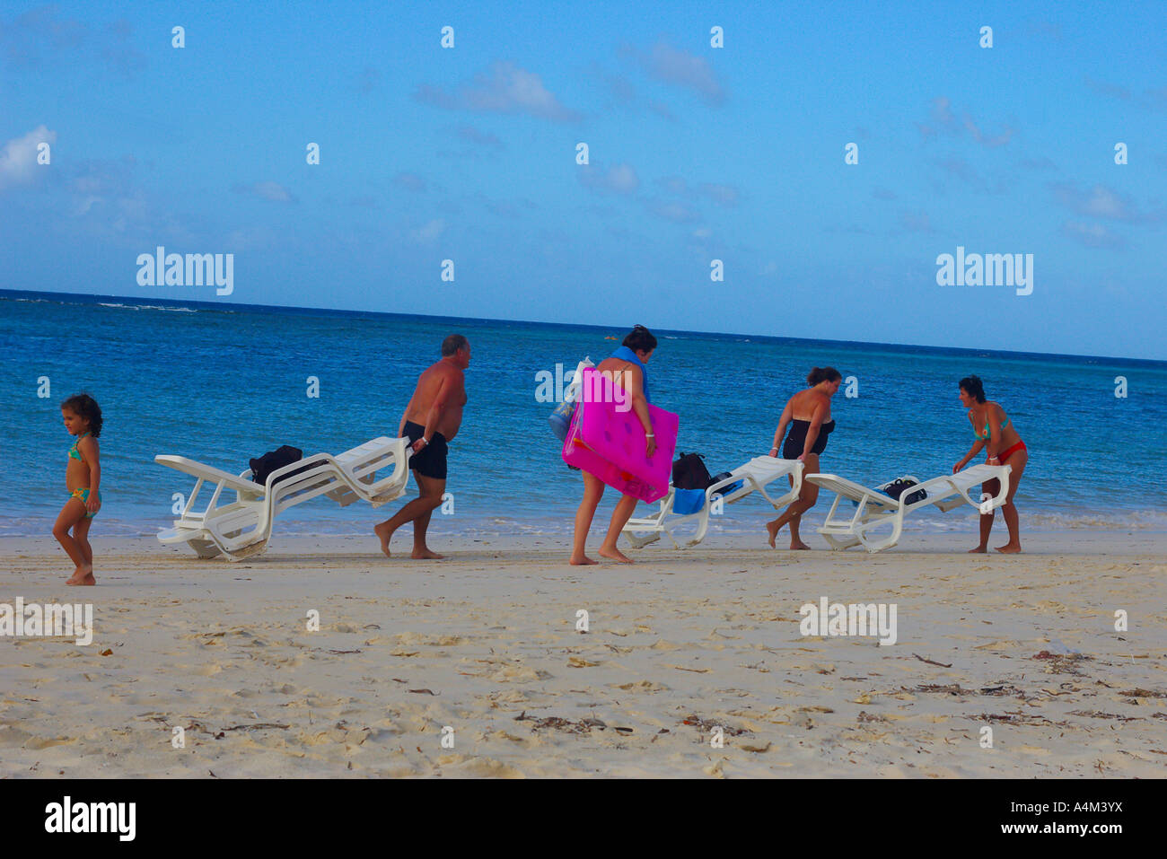 Eine Comic-Urlaub-Szene von Urlaubern, die Liegestühle am Strand Guadarlavaca Guardalavaca Holguín Provinz Kuba bewegen Stockfoto