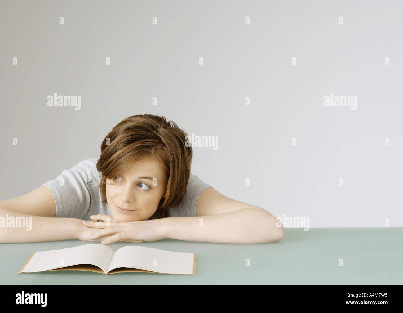 Junge Frau sitzt mit Kopf auf Tisch neben offenen notebook Stockfoto