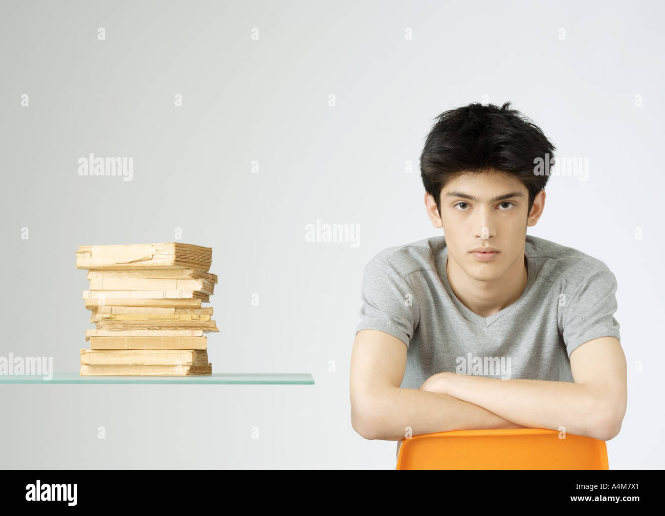 Junger Mann sitzt neben Stapel Bücher, Porträt Stockfoto