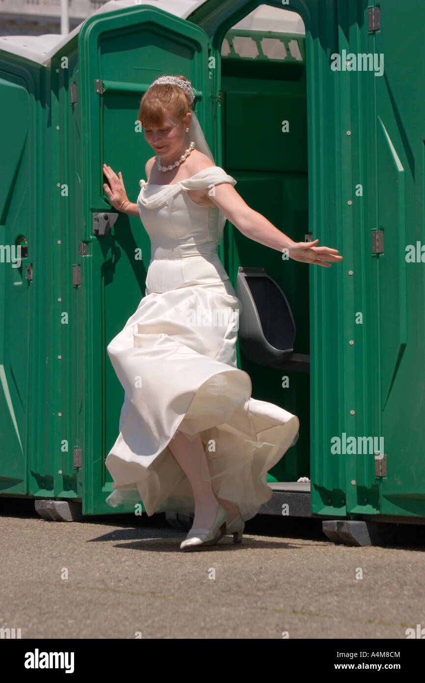 Eine hübsche Braut verlässt eine tragbare Toilette. Stockfoto