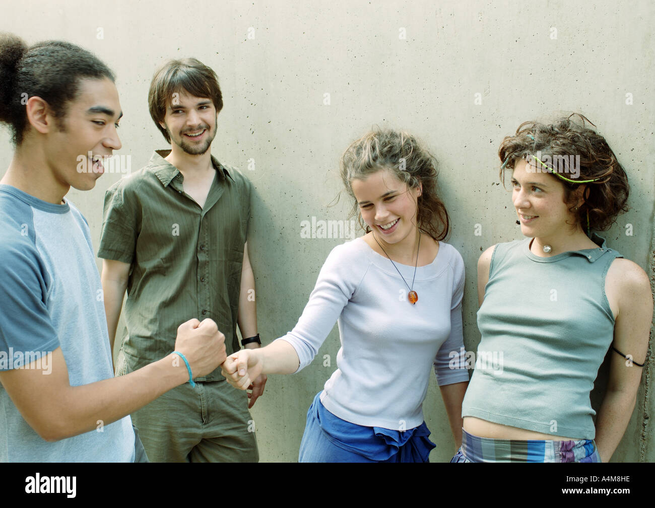 Vier junge Freunde stehend nahe bei der Wand, die Fäuste zwei berühren Stockfoto