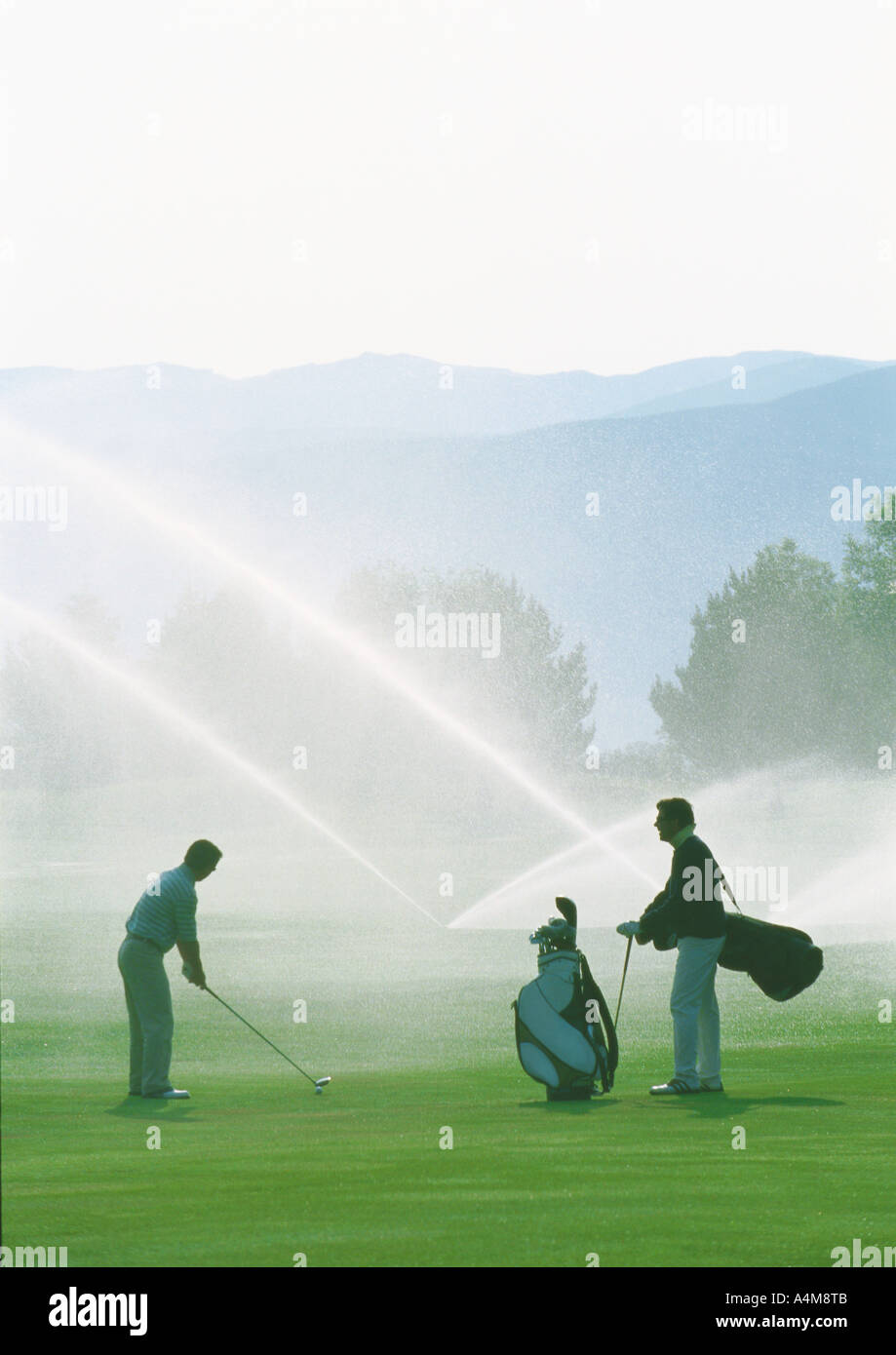 Golfer Golfen unter Sprinkler Stockfoto