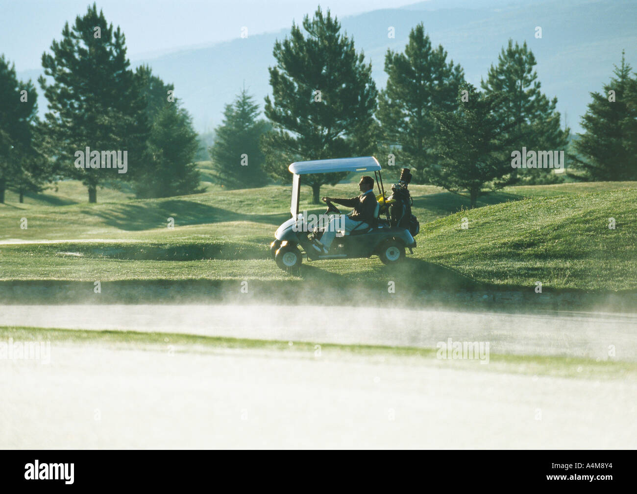 Golfer fahren Golf-Cart neben Sandfang Stockfoto