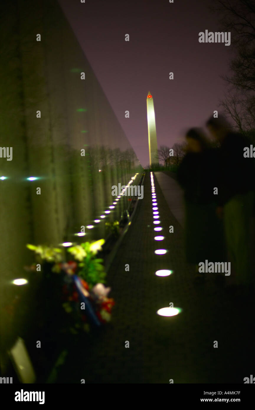 Paar besucht Vietnam War Memorial in der Nacht mit dem Washington Monument in der Ferne Washington DC USA Stockfoto