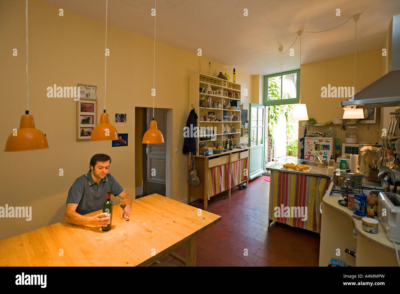 In der Küche, ein dreißig Jahre alte Mann blickte auf seine leere Flasche. Homme Trentenaire Contemplant Une Une Bouteille de vin vide. Stockfoto