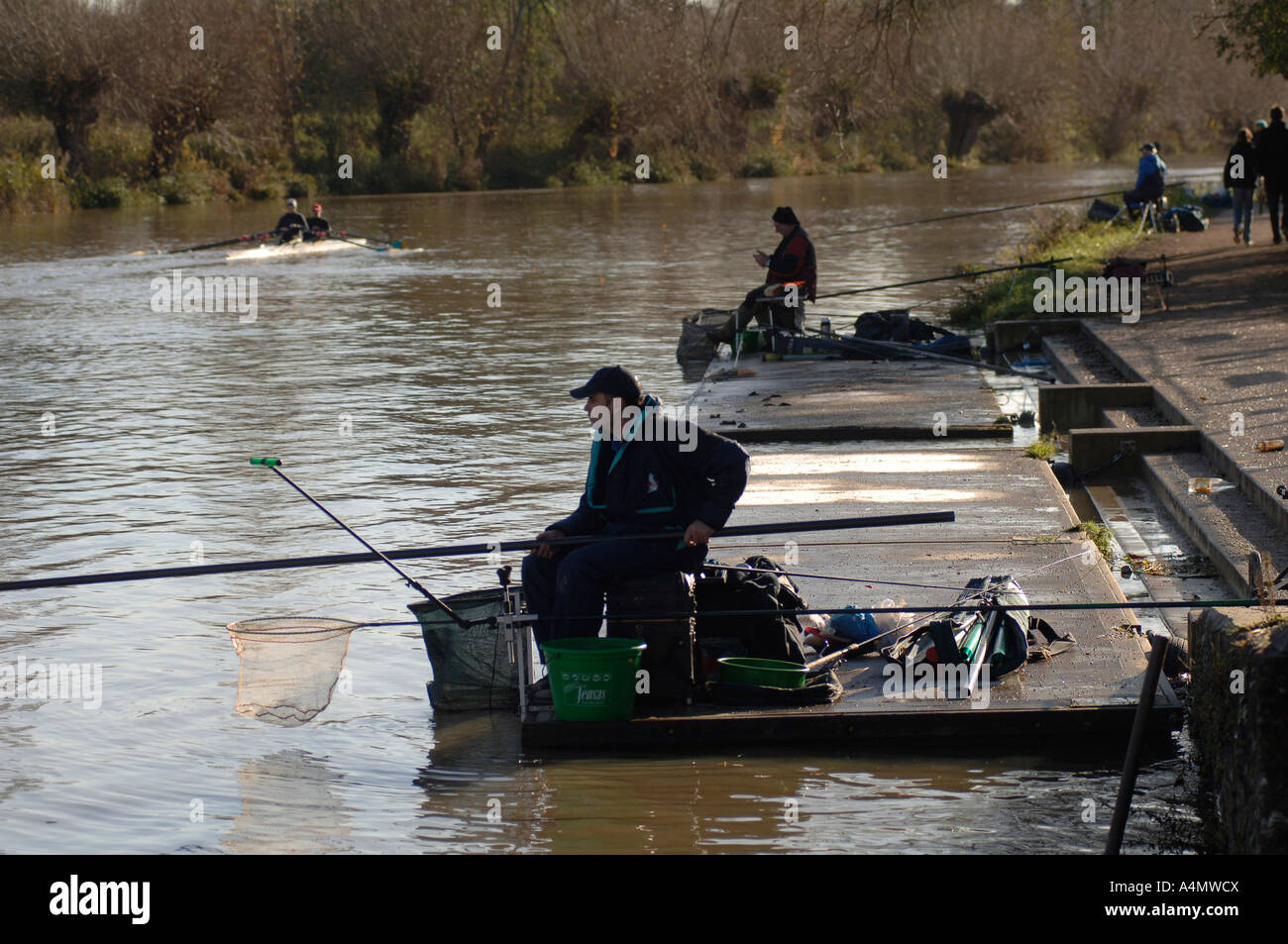 Ein Fischer auf der Seite der Isis, die Themse in Oxford an einem hellen Wintertag. Teilnahme an einem Kurs Angelwettbewerb Stockfoto