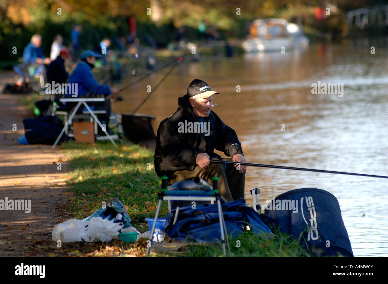 Ein Fischer auf der Seite der Isis, die Themse in Oxford an einem hellen Wintertag. Teilnahme an einem Kurs Angelwettbewerb Stockfoto