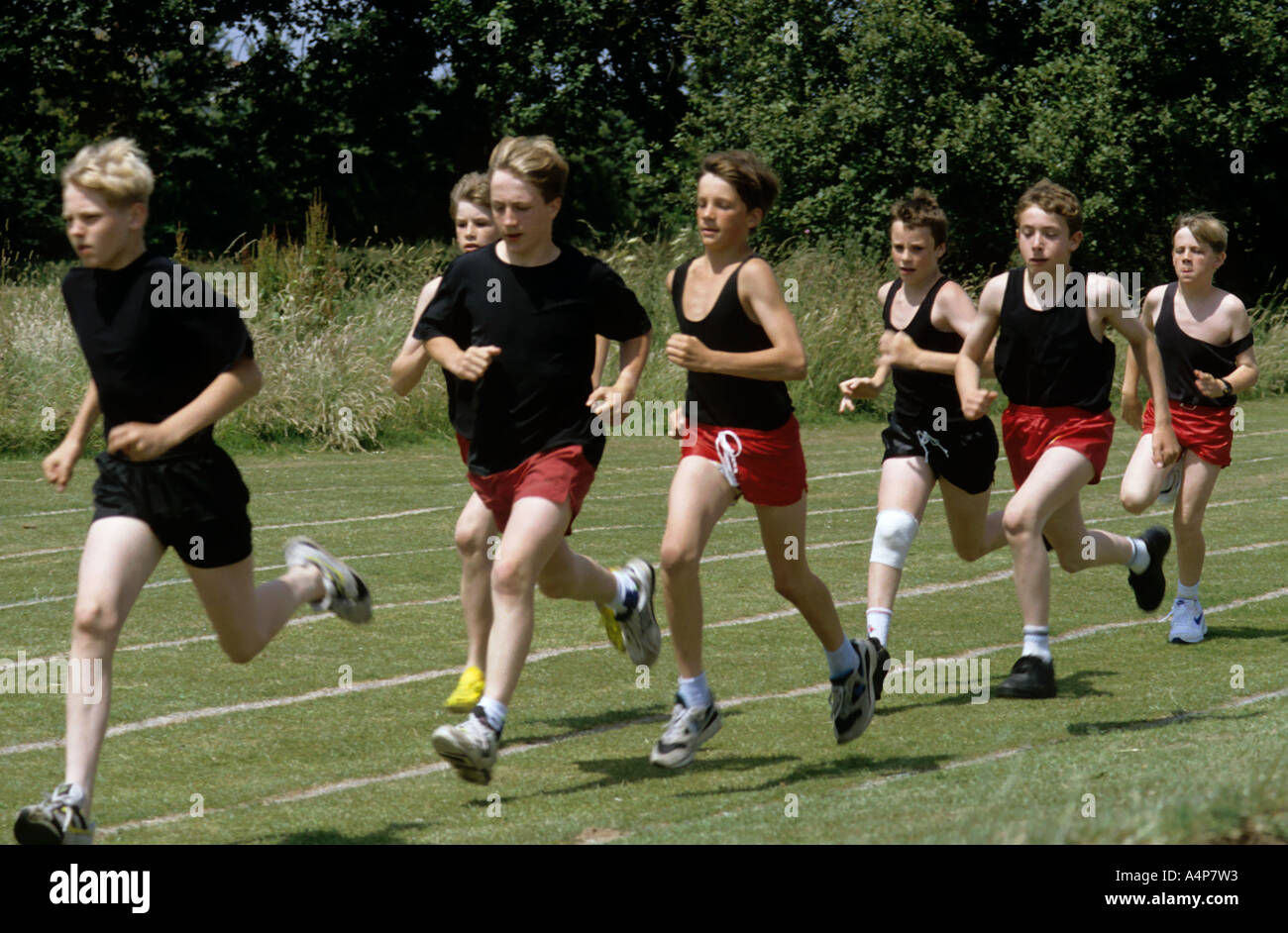 Gruppe von Schuljungen läuft lange Strecken um einen Rasen verfolgen Wales UK Stockfoto
