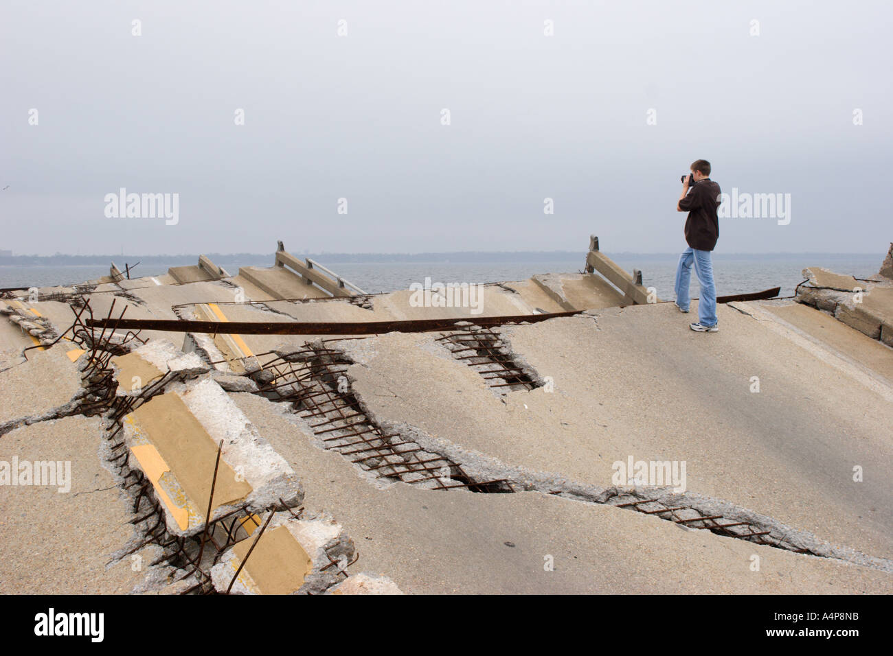 Männlicher Teenager, der auf Überresten der Draw Bridge steht, die Ocean Springs mit Biloxi, Mississippi über der Back Bay nach Hurrikan Katrina verbindet Stockfoto