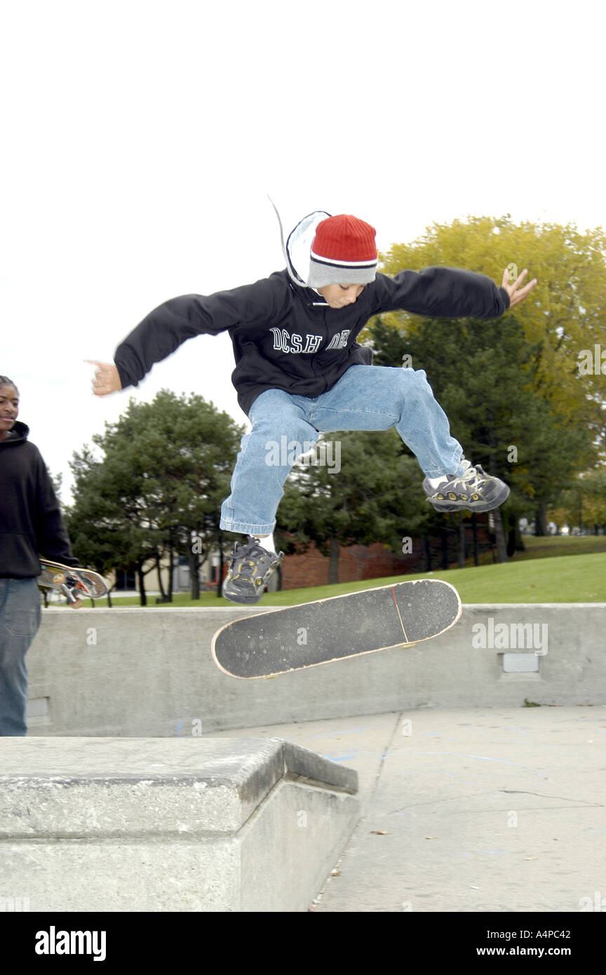 Teenie jungen Manöver auf einem Skateboard in einem öffentlichen park Stockfoto