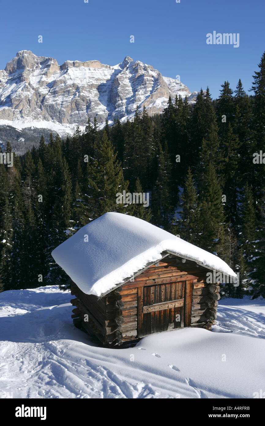 Holzhütte im Wald und die Berge des Dolamites im Winterschnee, Italien Stockfoto