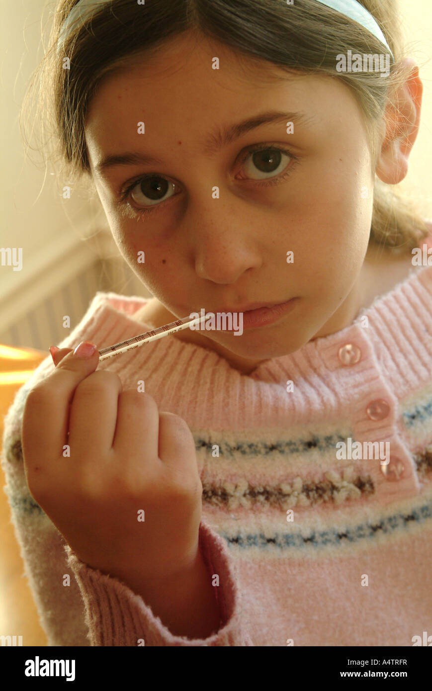 Eine Mädchen mit einem möglichen Fieber prüft ihre Temperatur oral mit einem Glas-Quecksilber-Thermometer Herr Stockfoto