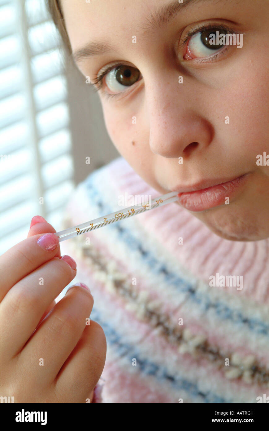 Eine Mädchen mit einem möglichen Fieber prüft ihre Temperatur oral mit einem Glas-Quecksilber-Thermometer Herr Stockfoto