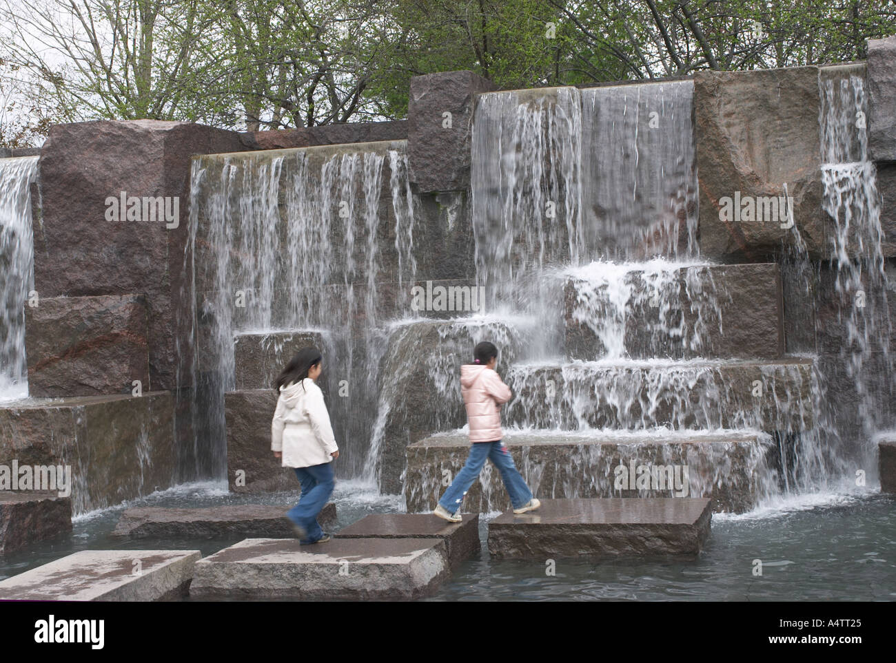 Zwei asiatische Kinder gehen unter den Wasserfällen am FDR Memorial in Washington, D.C. Stockfoto