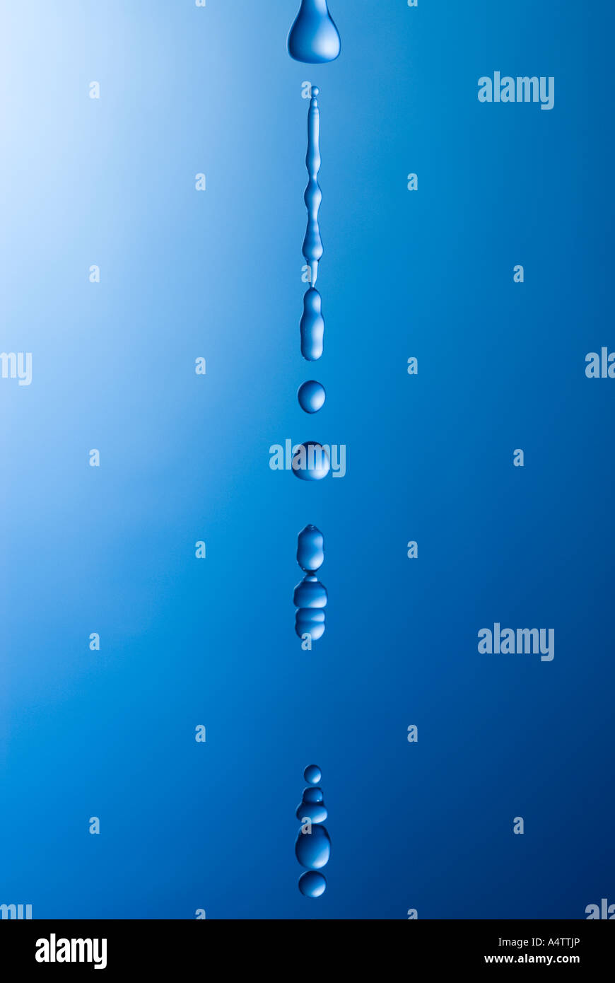 blaues Wasser Tropfen fallen vor einem blauen und weißen Hintergrund Stockfoto