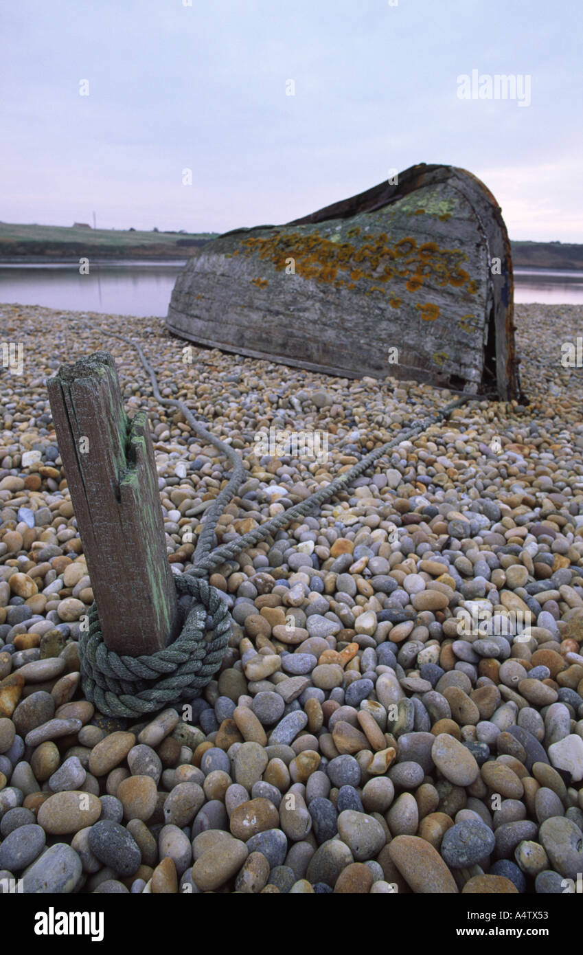 Alten Holzboot, gebunden an einen Pfosten auf Chesil Beach in Dorset county England UK dieses Foto entstand im Dezember Stockfoto