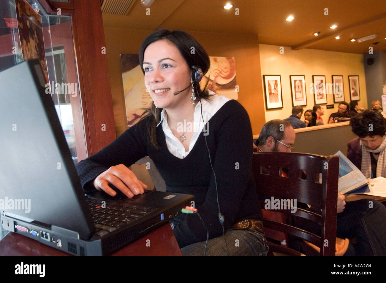 Junge Frau mit Skype auf einem Laptop-Computer an einem Wifi-Hotspot in Starbucks Coffee-Shop, London, England UK Stockfoto