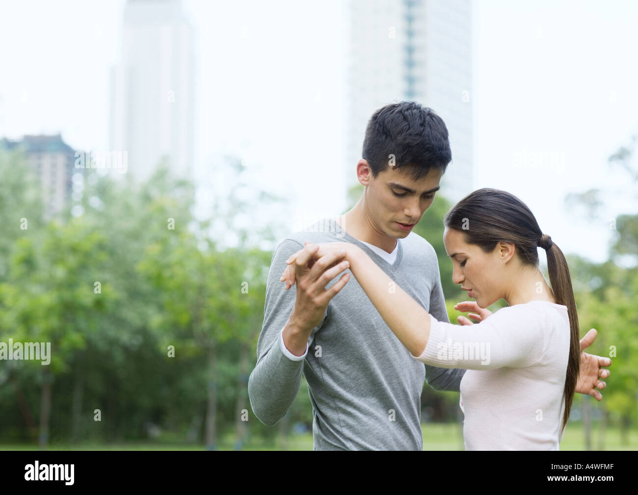 Junge Frau unterrichten jungen Mann zum Tanz im Stadtpark Stockfoto