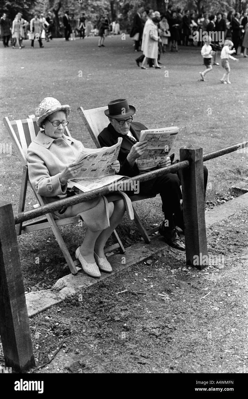 Älteres Paar liest Zeitungen St James Park Central London sitzt auf Liegestühlen, Liegestühle, England 1971 1970er UK HOMER SYKES Stockfoto