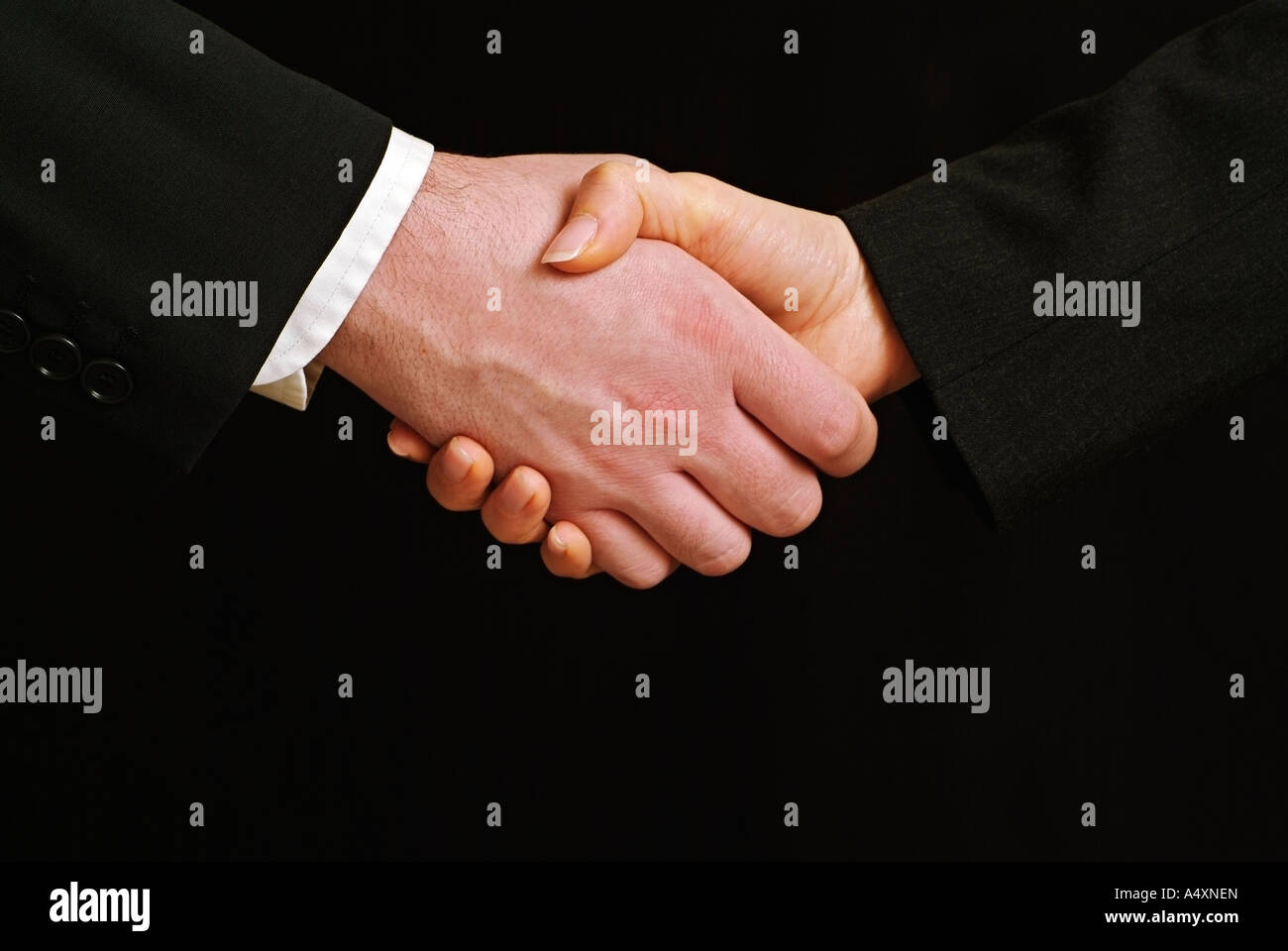 Männliche und weibliche Geschäftsleute Händeschütteln gegen einen schwarzen Hintergrund schließen sich Stockfoto