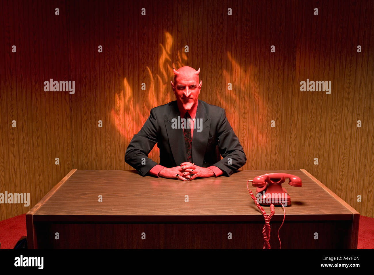 Geschäftsmann, verkleidet als Teufel am Schreibtisch Stockfoto