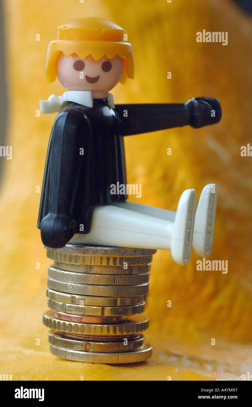Auf einem Stapel von Euro-Münzen sitzend Figur (Playmobil). Stockfoto